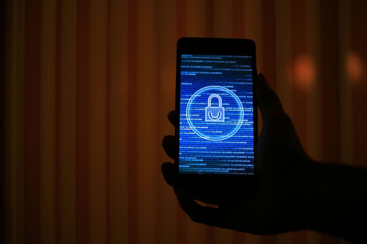 silhouette hand holding smart phone with padlock icon over blue binary code on screen display. cyber security concept. dark and ambiguous. how do we know that our privacy is not at risk.